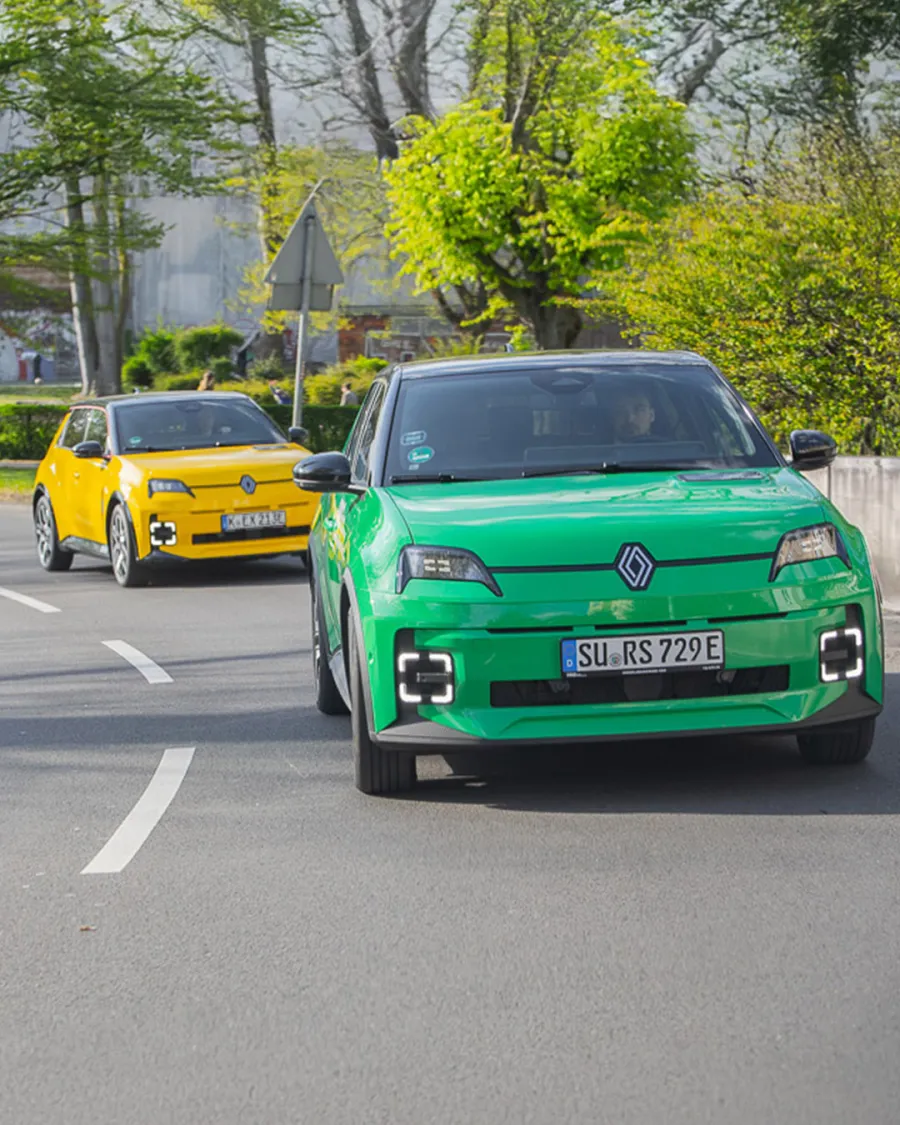 Gelber Renault 5 E-Tech auf einem Kopfsteinpflaster-Platz vor dem Kölner Dom, im Hintergrund ein grüner Renault 5